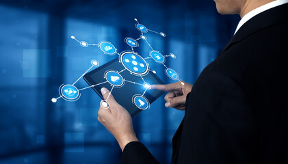 Business professional using digital tablet to interact with network of technology icons in modern office environment showcasing innovation and connectivity. Tessel.