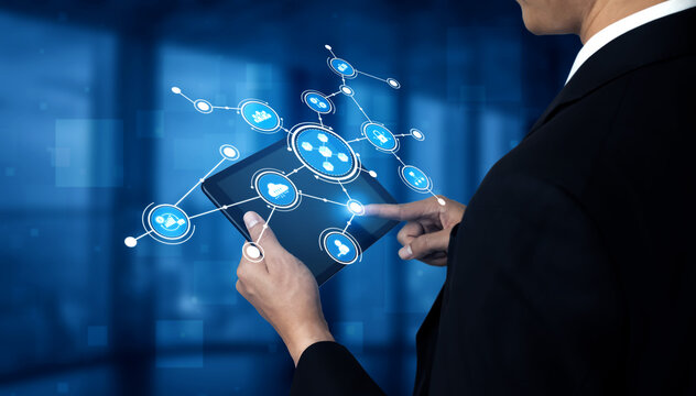 Business professional using digital tablet to interact with network of technology icons in modern office environment showcasing innovation and connectivity. Tessel. - Powered by Adobe