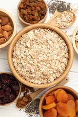 Making granola. Oat flakes, dried fruits and other ingredients on white wooden table, flat lay