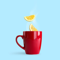 Citrus drink for health boosting. Lemon pieces falling into cup on light blue background. Cold season remedy
