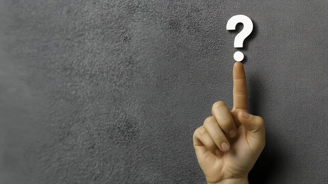 Closeup of a person&rsquo;s finger pointing at a question mark on a textured wall with a contemplative atmosphere