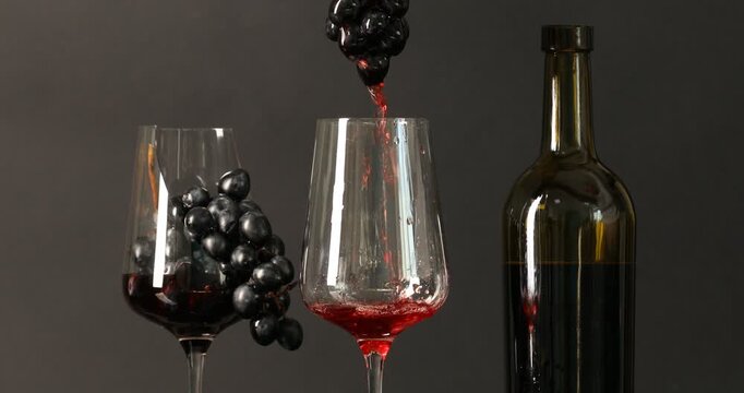 Pouring red wine into glass through grapes on black background, closeup
