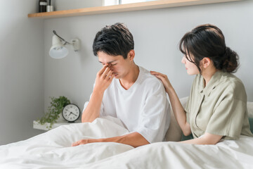 Fototapeta premium A man suffering from eye strain, dry eyes, cataracts, and glaucoma in the morning bedroom and a worried woman, married couple, and couple 