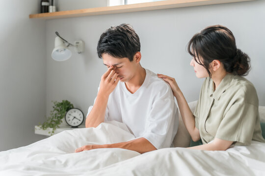 A man suffering from eye strain, dry eyes, cataracts, and glaucoma in the morning bedroom and a worried woman, married couple, and couple
