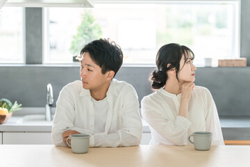 A young couple with cold expressions sitting in the dining room (marital relationship, boredom, rut, fake marriage, marital quarrel)
