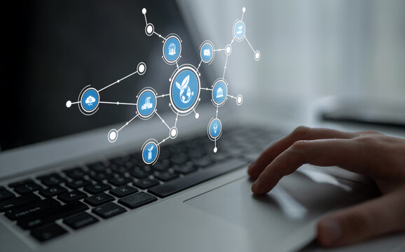 A close-up view of a hand on a laptop keyboard with floating icons representing digital connectivity, technology, and innovation illustrating modern business themes. Tessel - Powered by Adobe