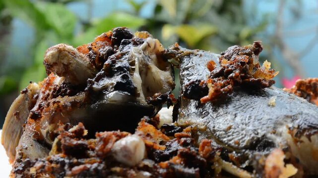 Extreme Close-up Macro Shot of Crispy Fried Catfish Head (Ikan Lele) with Dark Spices and Crunchy Bits. Authentic Asian Street Food and Local Cuisine