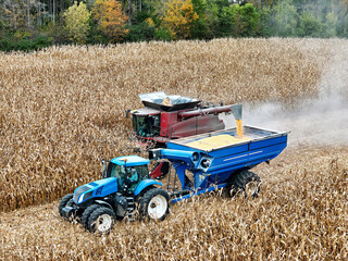 Fototapeta premium Aerial view of a combine offloading corn into a grain cart being pulled by a tractor