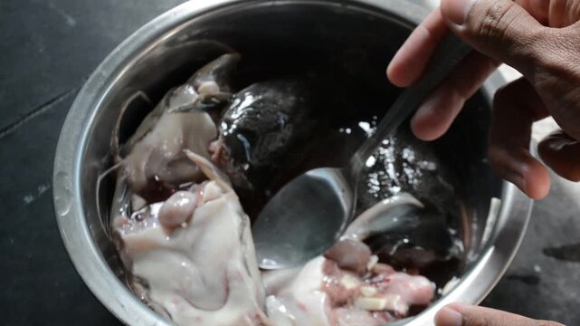 High-Angle Close-up of Raw Catfish (Ikan Lele) Being Cleaned and Washed in a Stainless Steel Bowl by Hand. Food Preparation, Cooking, and Local Fish Market