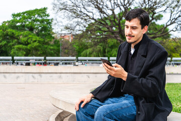 Obraz premium Young man using phone in park