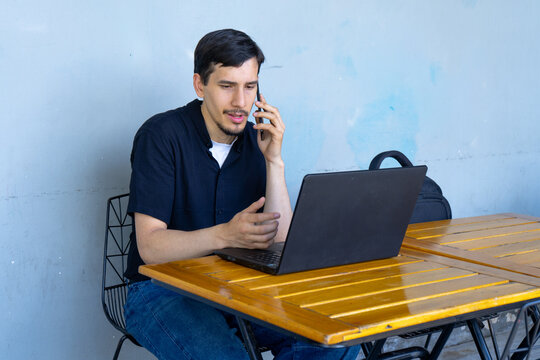 Young man remote working talking on smartphone