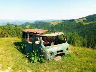 Abandoned rusty minibus overgrown in mountains