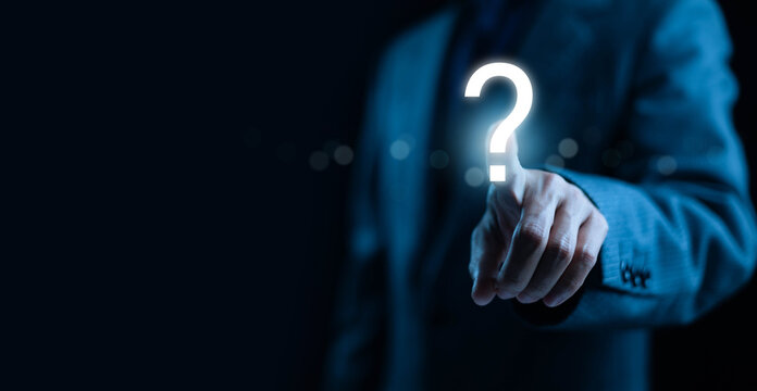 A businessman pointing at a glowing question mark icon symbolizing uncertainty decision-making inquiry problem-solving, and strategic planning in modern digital business and professional environments.