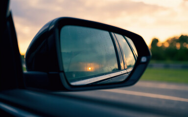 Golden sunset reflecting in car side mirror on a highway adventure offering a sense of freedom, travel, and calm with a touch of mystery and the open road