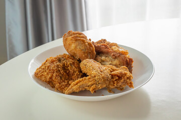 Crispy fried chicken in white plate on wood table
