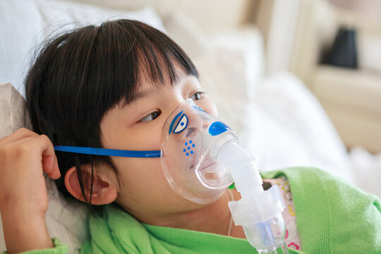Sick little asian girl inhalation with nebulizer for respiratory treatment