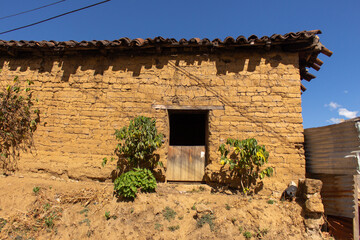 Rustic adobe house in San Juan La Laguna with textured earthen walls wooden doorway clay roof tiles...