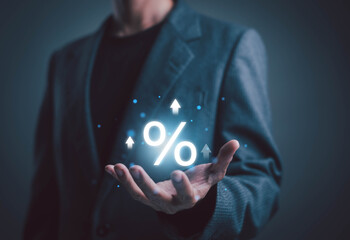 A businessman presenting a glowing percentage symbol with upward arrows, representing financial growth, rising interest rates, increased revenue, and positive economic performance in modern business.