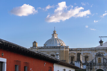 Historic colonial dome and rooftops in Antigua Guatemala under a blue sky with soft clouds...