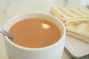 Warm cup of milk tea served with toasted bread in cafe