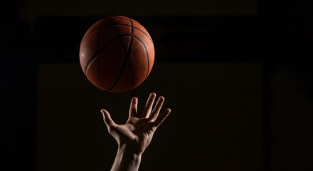 Basketball Player Hand Reaching for Orange Basketball in Dark Indoor Court