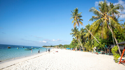 tropical beach with coconut palm trees and blue sky at Bara beach, Bira Bay