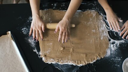 Hands roll ginger cookie dough on a floured table as a mother and daughters work together in a warm kitchen environment, enjoying a shared homemade baking experience and family connection concept
