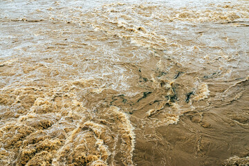Smudged water flows profusely. River water flowing profusely. Flood waters rushing down river after storm flows through. Turbulent river dam. Water turbulence of river due to dam. Water Nature Texture