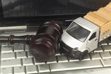 Truck model with many carton boxes and judge gavel on laptop computer close up. Legal regulation of...