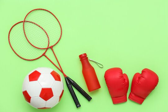Sport equipment with boxing gloves and soccer ball on green background. Top view
