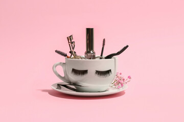 Cup with false eyelashes, mascara and tools on pink background