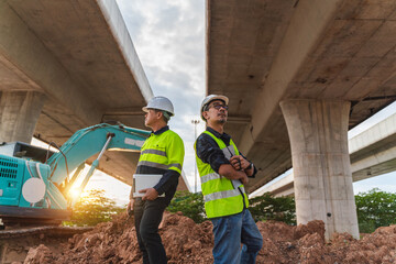 Construction Workers Overseeing Road Development Project Under Elevated Highway Structure with...