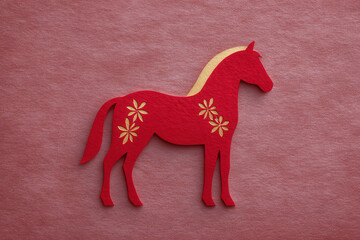 Red paper horse with gold floral pattern, symbolizing luck and celebration, stands on textured pink background, representing Chinese New Year and traditional craft with festive, joyful mood