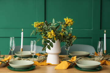 Elegant table setting with glasses, burning candles and blooming tree branches