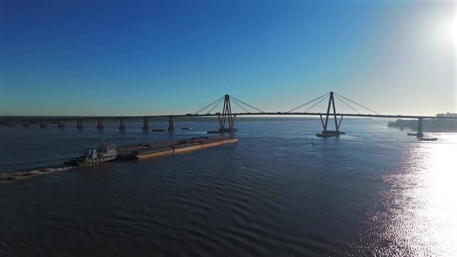 Cargo barge navigating the Paran&aacute; River with the General Belgrano Bridge in Corrientes, Argentina.