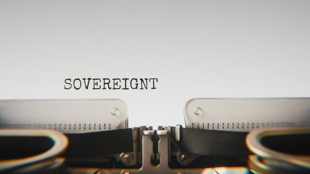 Old mechanical typewriter typing Sovereignty in a close-up view, with metal letters striking the white paper.