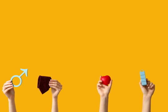 Female hands with symbol of man, heart and necktie on yellow background. Prostate Cancer Awareness Month