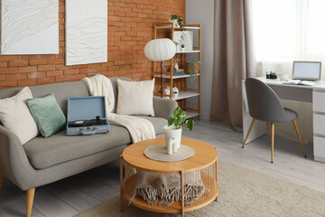 Interior of living room with record player on sofa, tables and lamps