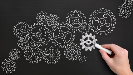 Business operation. Businessman drawing gears on chalkboard