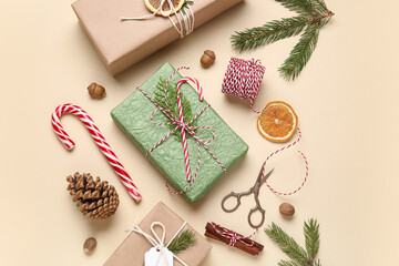 Gift boxes wrapped in eco paper with Christmas decorations, dried oranges and packing materials on beige background