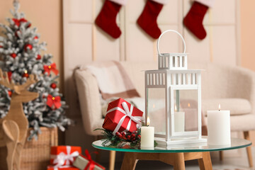 Christmas lantern with gift boxes and candles on table in living room
