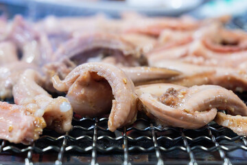 roasting pieces of raw eels on a charcoal grill in a Korean restaurant