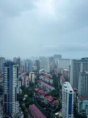 Obraz premium City skyline under cloudy sky with buildings and rooftops visible during rainy weather