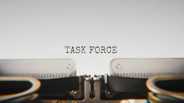 Old mechanical typewriter typing Task Force in a close-up view, with metal letters striking the white paper.