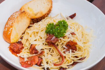 Spaghetti with bacon on white dish
