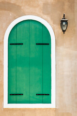 Green window on concrete wall with lamp.