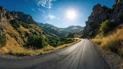 Naklejka premium Scenic winding road through a sunny mountain valley with clear blue sky