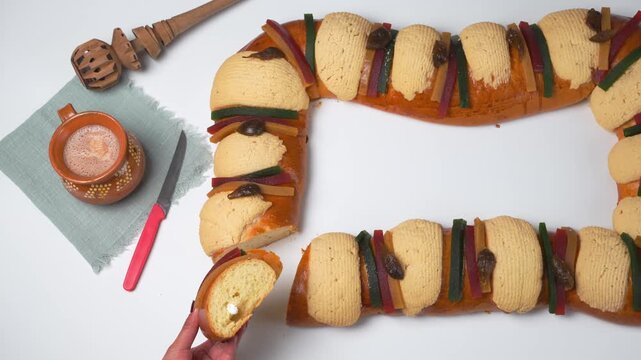 A hand finds a figure inside the rosca de reyes or king cake, a celebration of the Epiphany