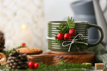 Wooden board with mug of tasty rose hip tea, cookies and fir branches on grey background