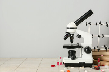 Molecular model with microscope, books, ampules and pills on tile against grey background. Nobel...